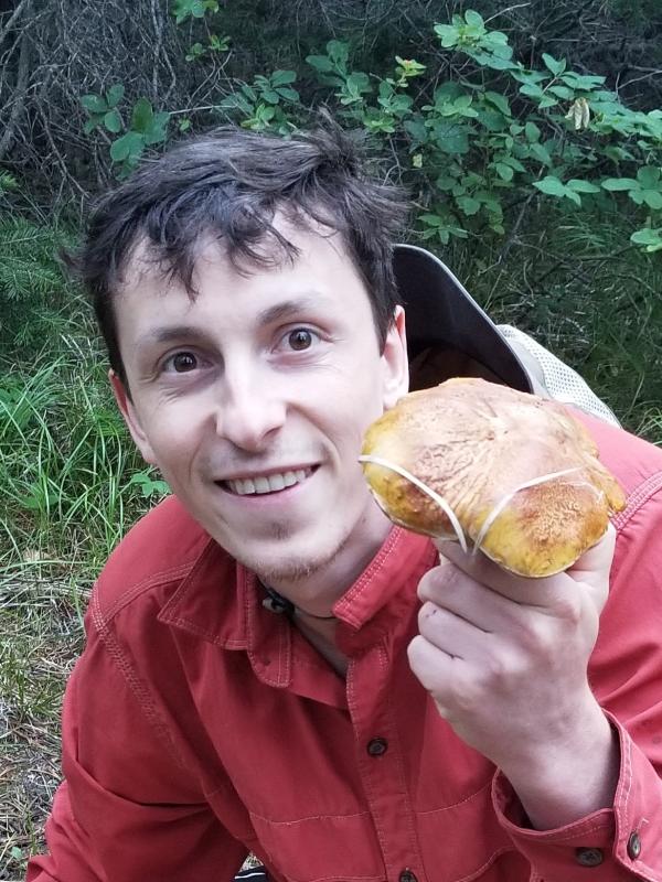 TPS Fellow Zach Konkel holding a mushroom in the field